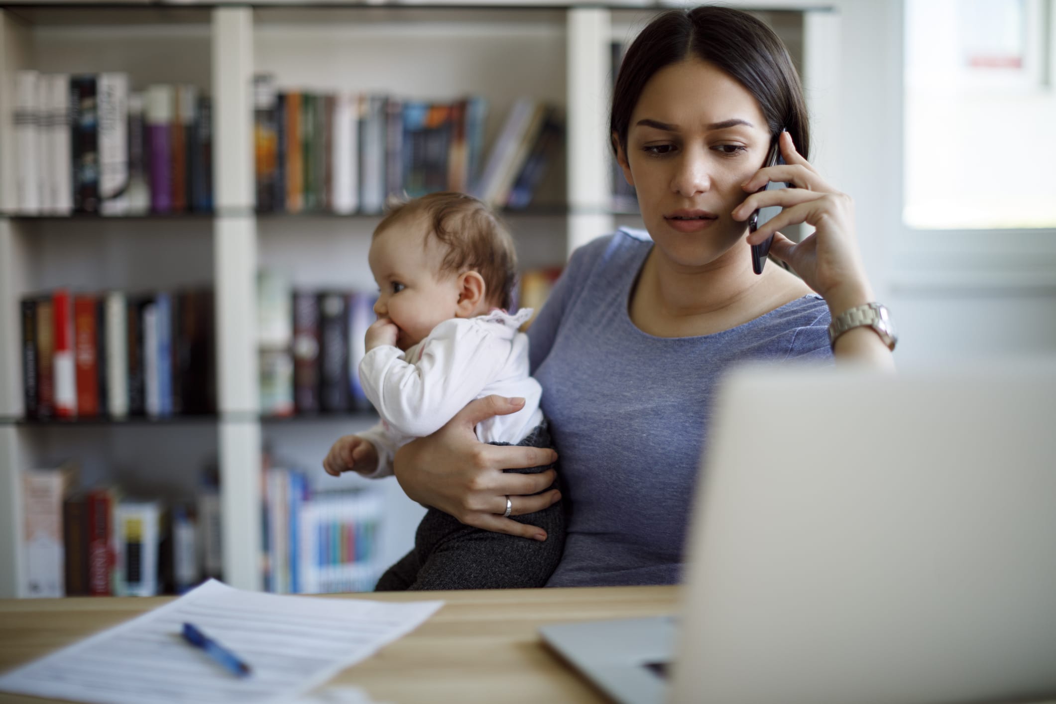 Worried mother using mobile phone an laptop at home